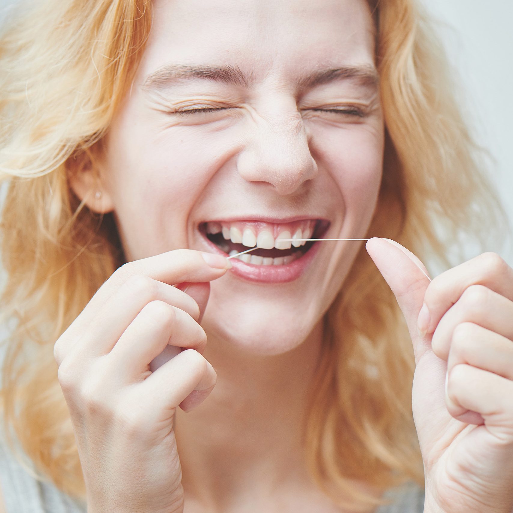 Foto Dr. Feyer - Fachpraxis für Kieferorthopädie - Frau nutzt Zahnseide